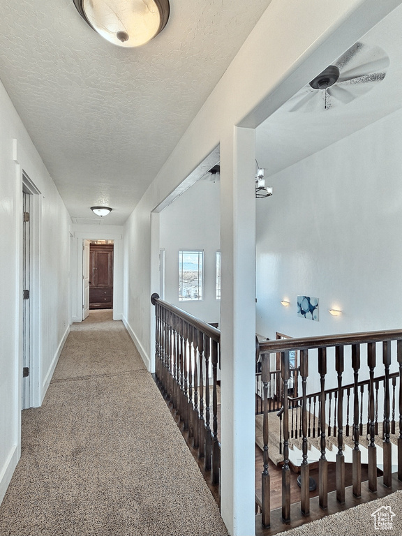 Hall featuring carpet flooring, a textured ceiling, and a chandelier
