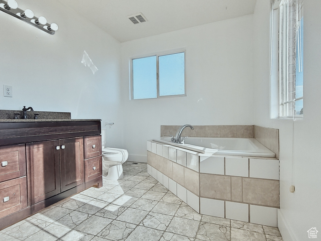 Bathroom with vanity, a tub to relax in, and toilet