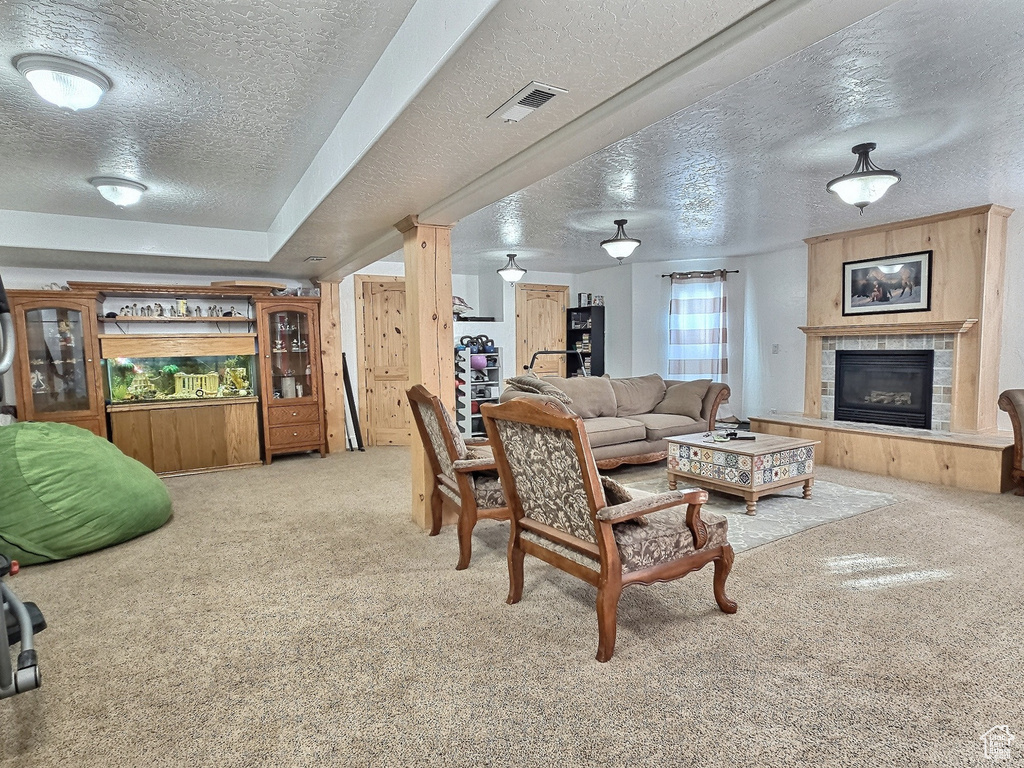 Living room featuring a textured ceiling, light carpet, and a tiled fireplace