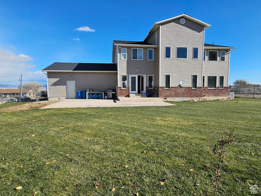 Back of property with a lawn and a patio