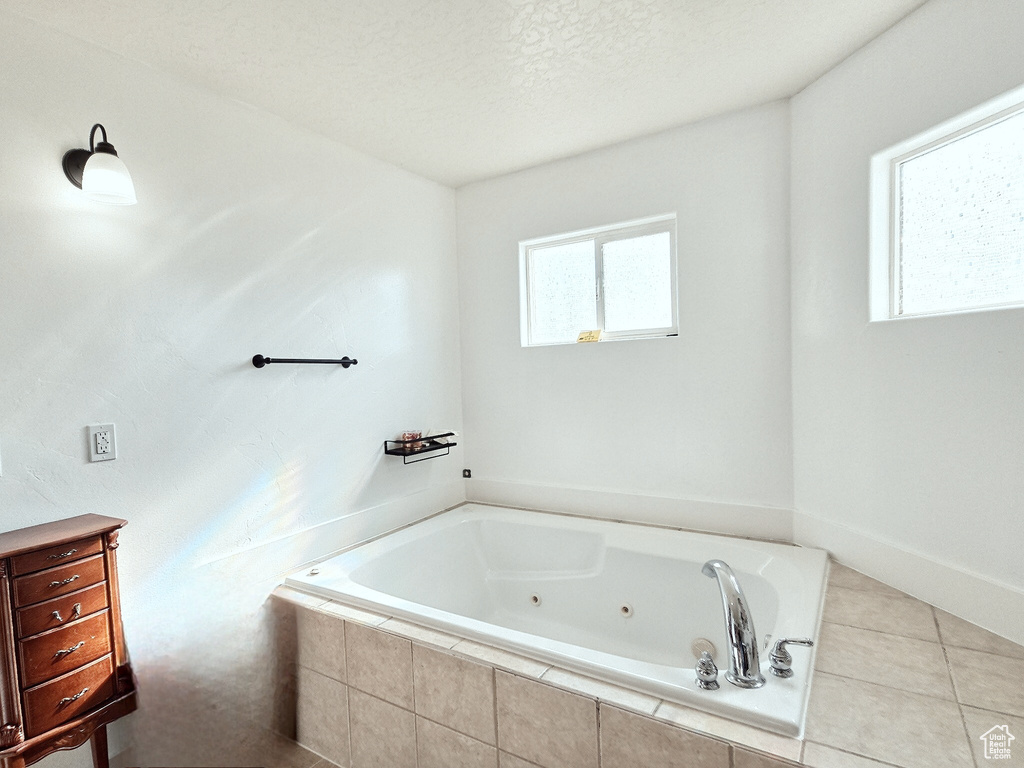 Bathroom featuring tile patterned flooring, a textured ceiling, and tiled bath