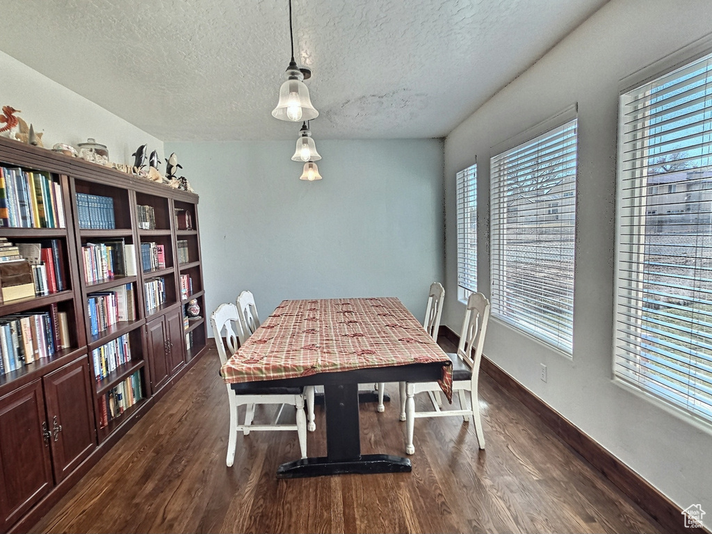 Dining area with a textured ceiling and dark wood-type flooring