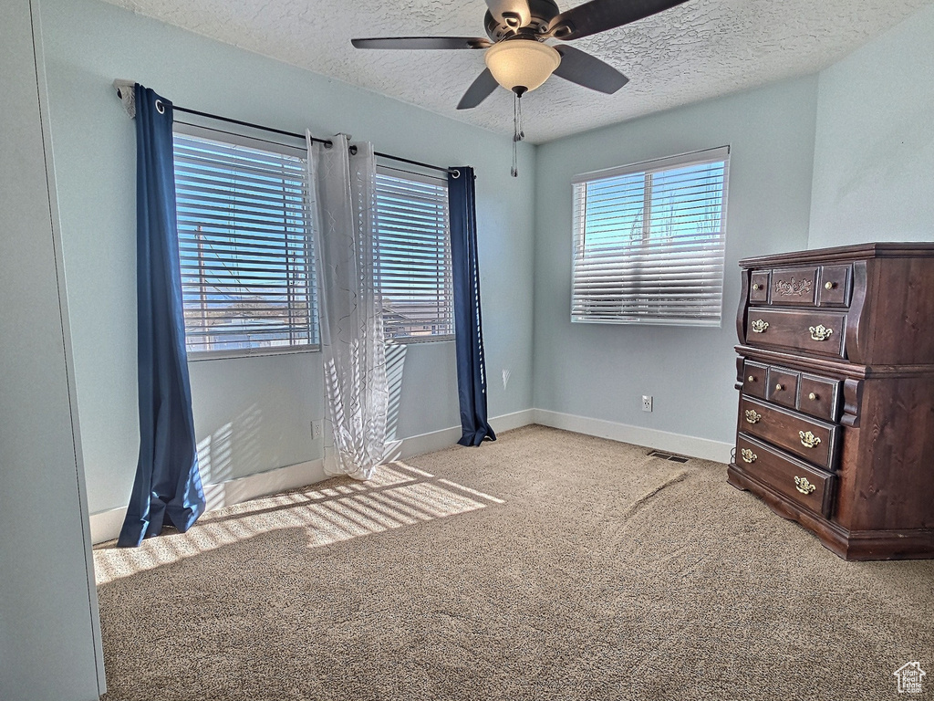 Unfurnished bedroom featuring ceiling fan, light colored carpet, and a textured ceiling