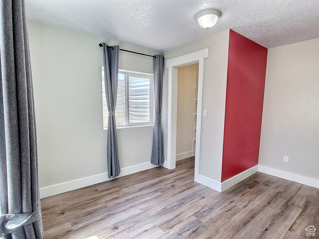 Unfurnished bedroom with a textured ceiling and light hardwood / wood-style flooring