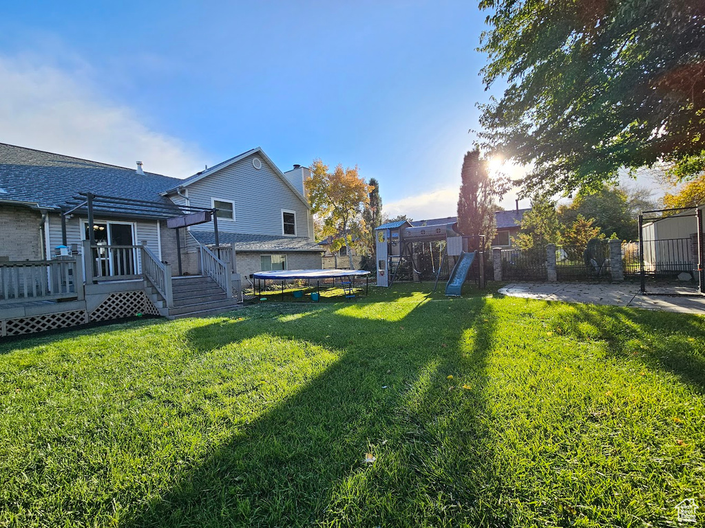 View of yard featuring a deck and a trampoline