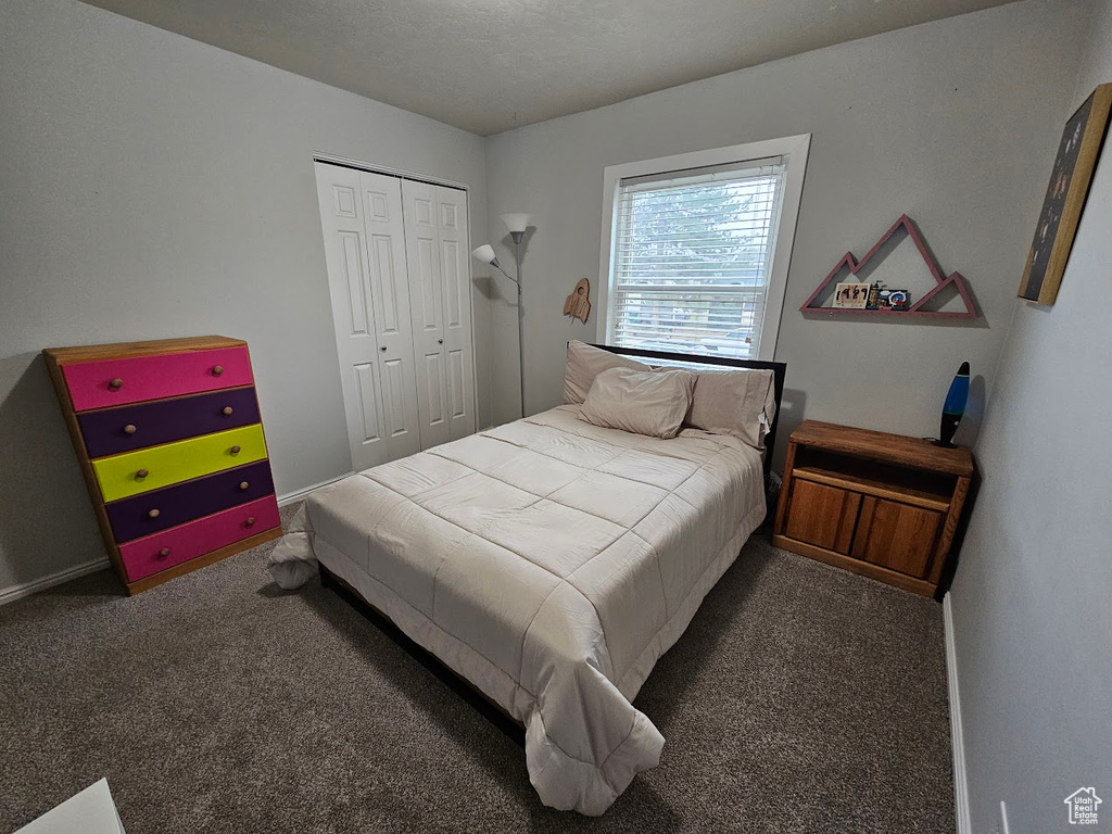 Bedroom featuring dark colored carpet and a closet