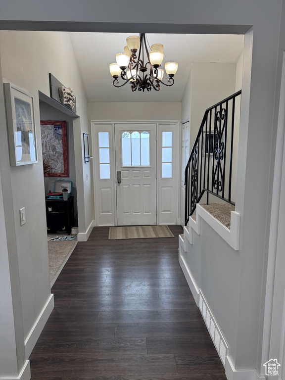 Entryway with dark hardwood / wood-style flooring, a notable chandelier, and vaulted ceiling