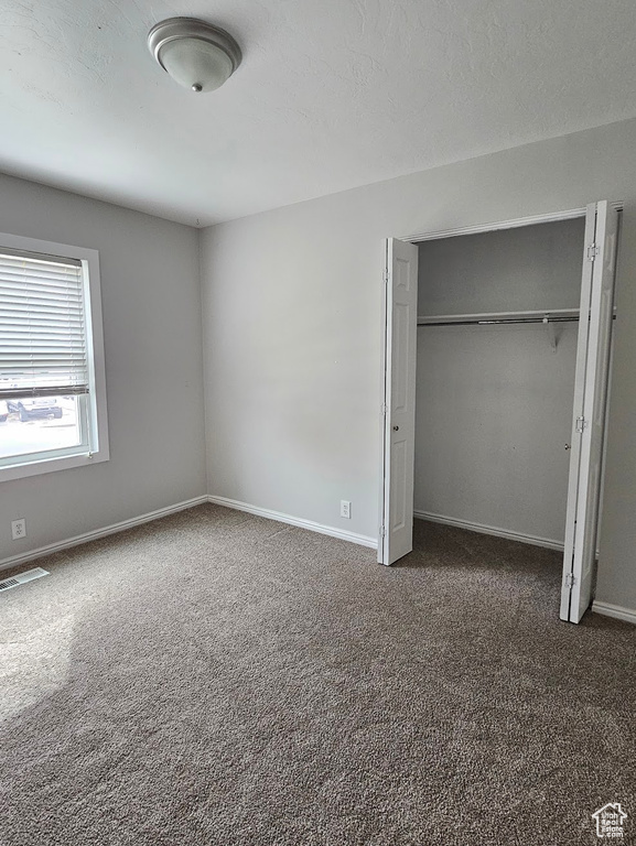 Unfurnished bedroom featuring a closet and dark carpet