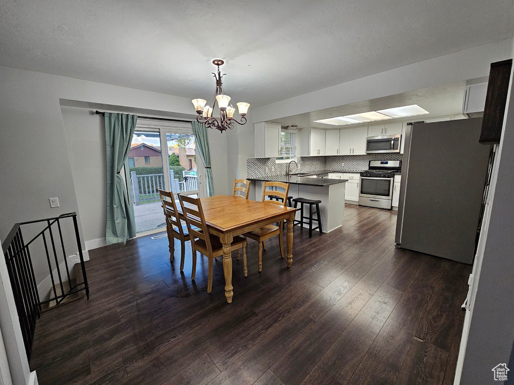 Dining room with dark wood-type flooring, sink, and a notable chandelier