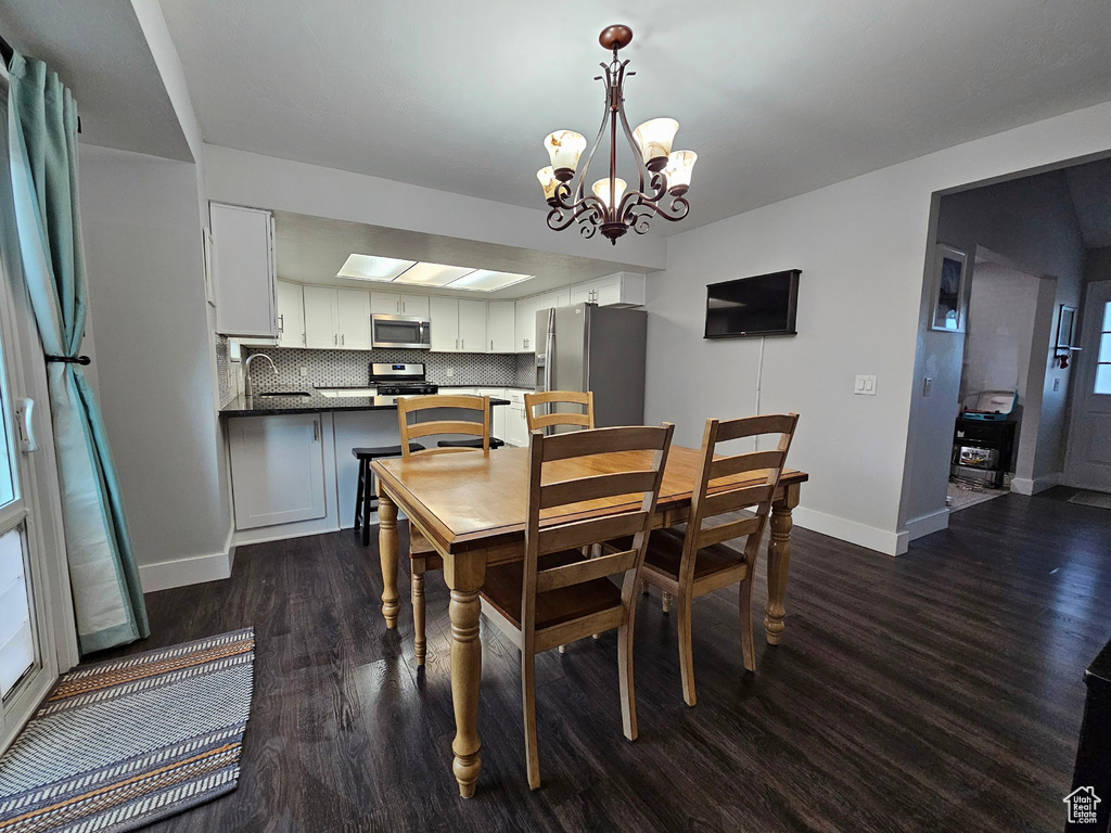 Dining area featuring dark hardwood / wood-style flooring, sink, and an inviting chandelier