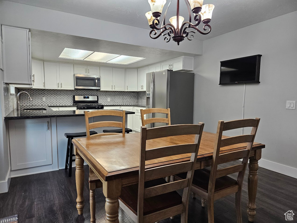 Dining space with dark hardwood / wood-style floors, sink, and an inviting chandelier