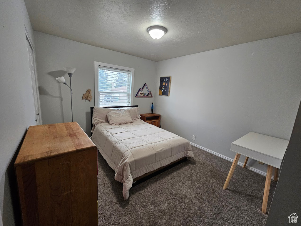 Bedroom featuring dark colored carpet and a textured ceiling