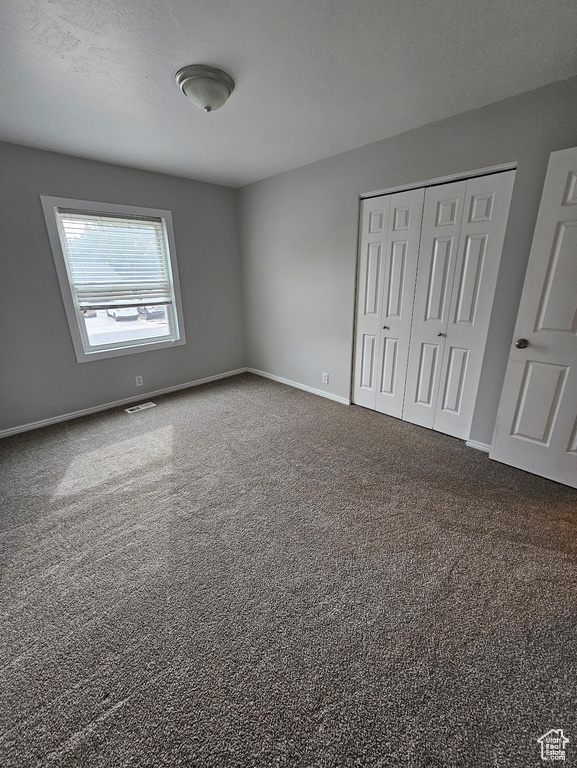 Unfurnished bedroom featuring a closet, a textured ceiling, and carpet flooring