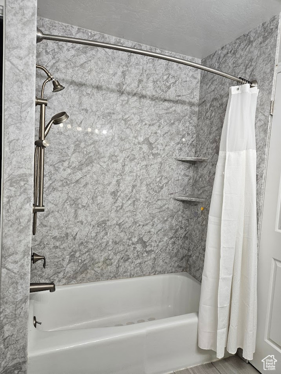 Bathroom with hardwood / wood-style flooring, a textured ceiling, and shower / bath combo with shower curtain