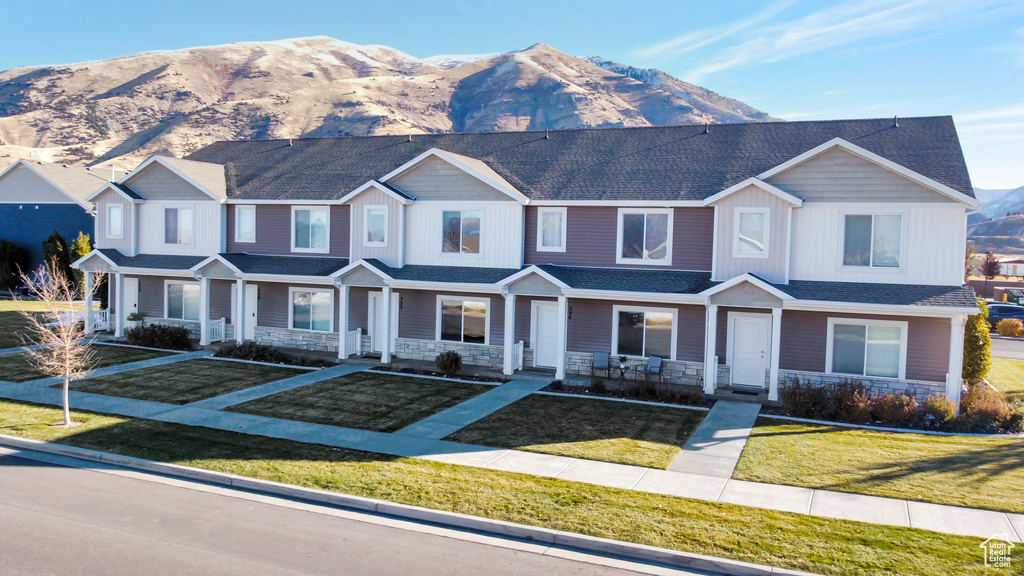 View of front of property featuring a front yard, a mountain view, and covered porch