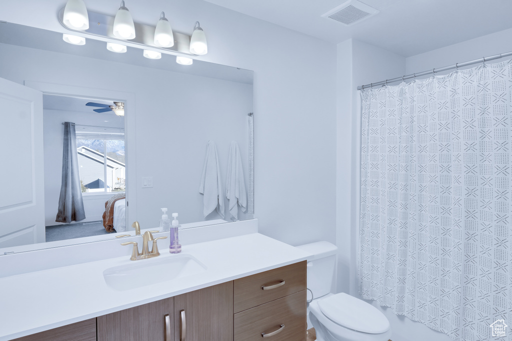 Bathroom with toilet, vanity, and ceiling fan