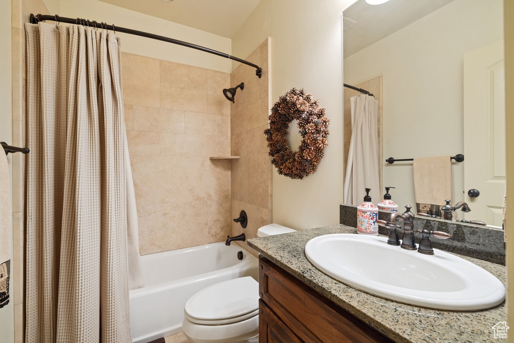 Full bathroom with shower / bath combo with shower curtain, vanity, and toilet
