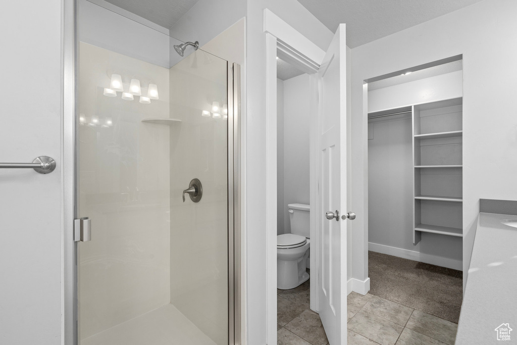 Bathroom with toilet, tile patterned flooring, and a shower with shower door