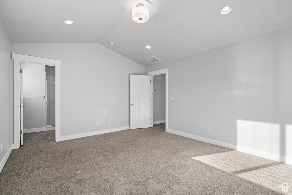 Unfurnished bedroom with a spacious closet, a closet, vaulted ceiling, and carpet