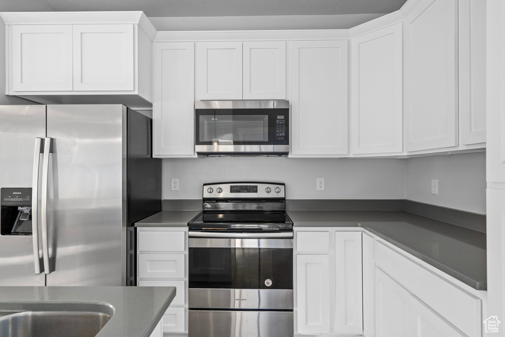 Kitchen with white cabinetry and appliances with stainless steel finishes