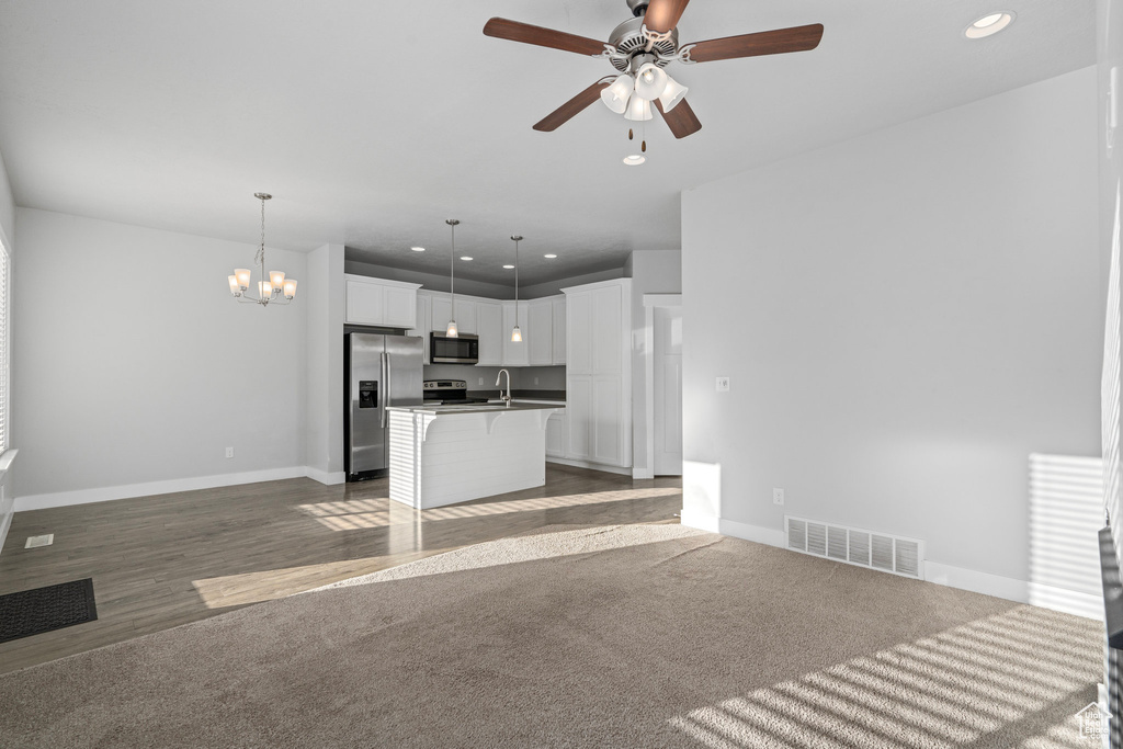 Kitchen featuring stainless steel appliances, a center island with sink, a breakfast bar, pendant lighting, and white cabinetry