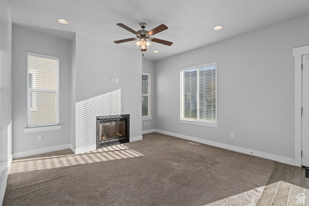 Unfurnished living room featuring ceiling fan and carpet floors