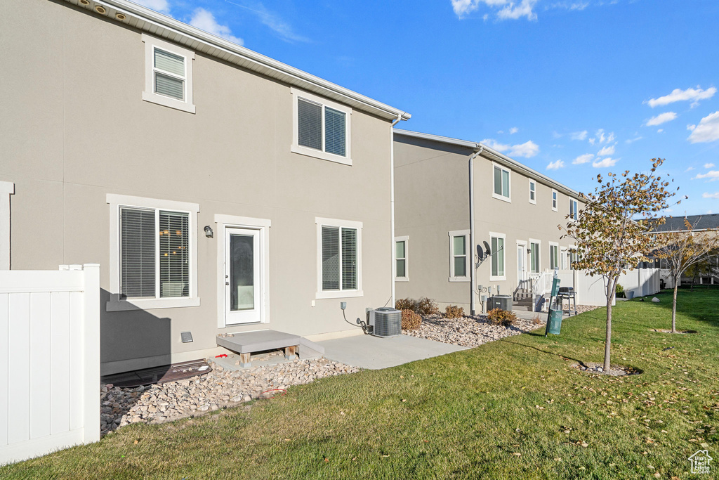 Back of property featuring central AC unit, a patio area, and a lawn