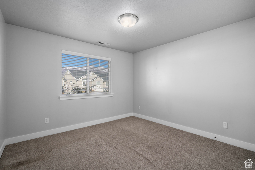 Carpeted empty room with a textured ceiling