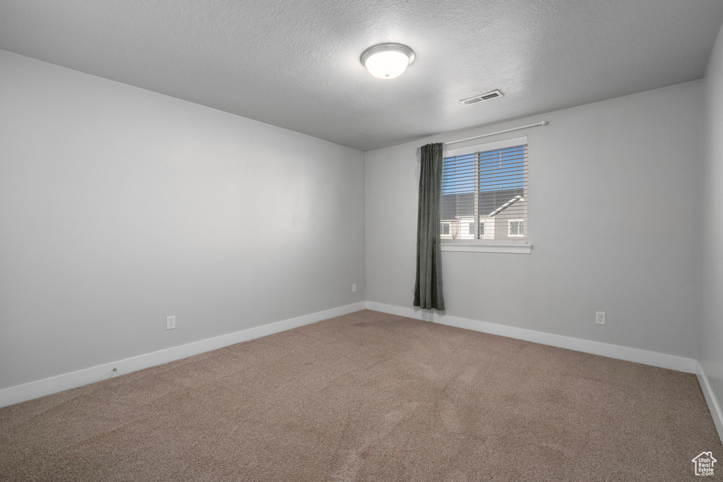 Carpeted spare room featuring a textured ceiling