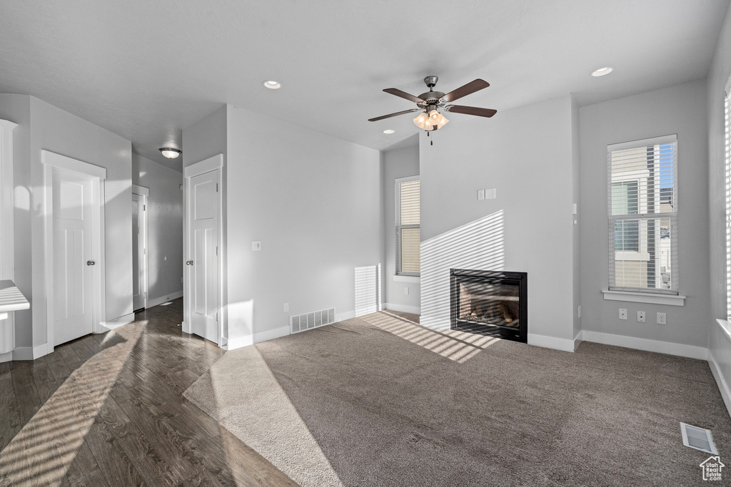 Unfurnished living room featuring dark wood-type flooring and ceiling fan