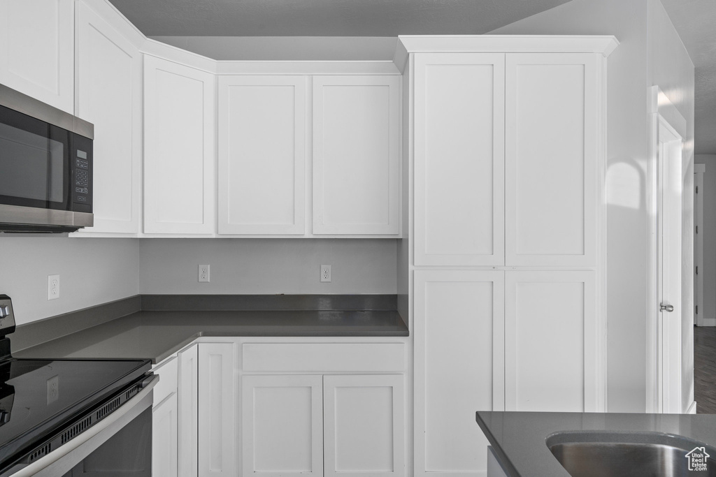 Kitchen featuring white cabinets, wood-type flooring, and black range with electric stovetop