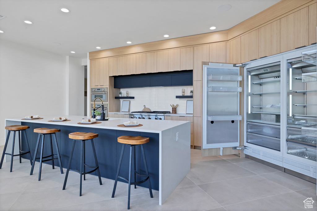 Kitchen featuring an island with sink, light tile patterned floors, and a breakfast bar area