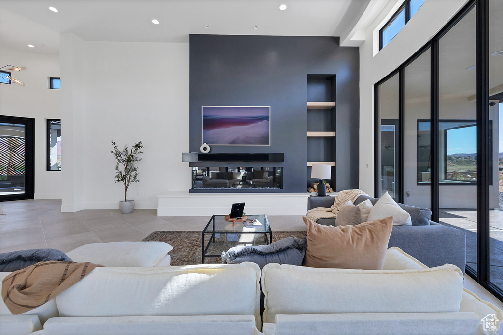 Living room with light tile patterned flooring, built in features, and a high ceiling