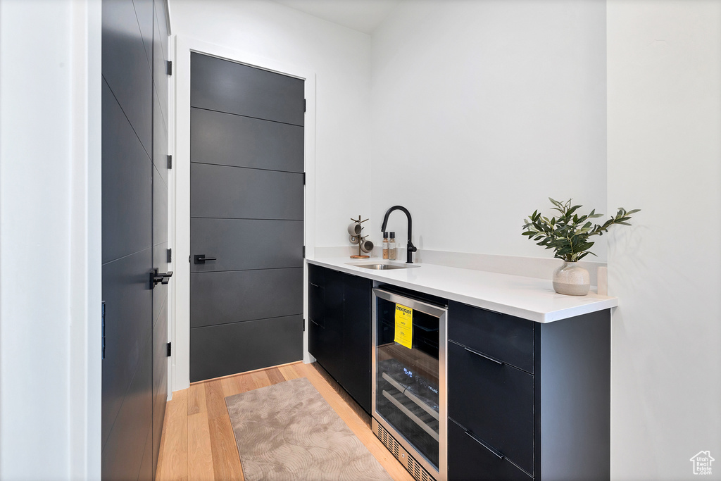 Bar featuring light hardwood / wood-style floors, wine cooler, and sink