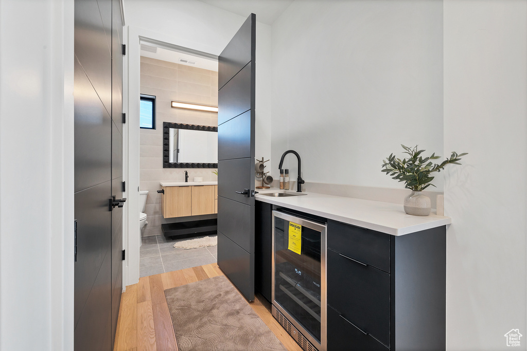 Bathroom with hardwood / wood-style floors, beverage cooler, vanity, toilet, and tile walls