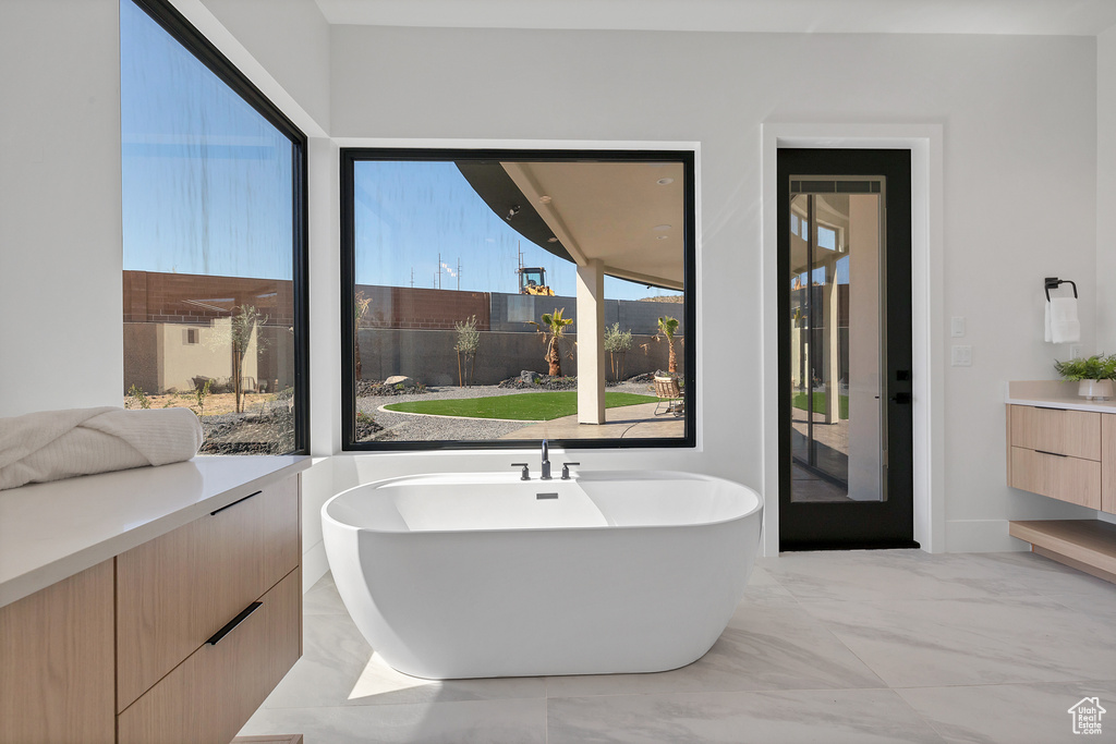 Bathroom featuring a tub to relax in, vanity, and plenty of natural light