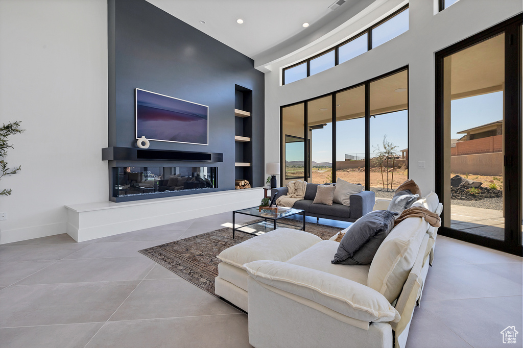 Tiled living room with a towering ceiling and built in shelves