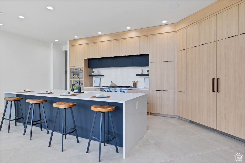 Kitchen with a spacious island, a breakfast bar area, and light brown cabinetry