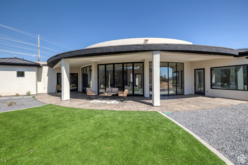 Rear view of house with outdoor lounge area, a lawn, and a patio