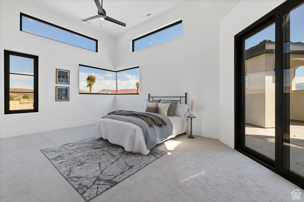 Bedroom with ceiling fan, multiple windows, access to exterior, and light colored carpet