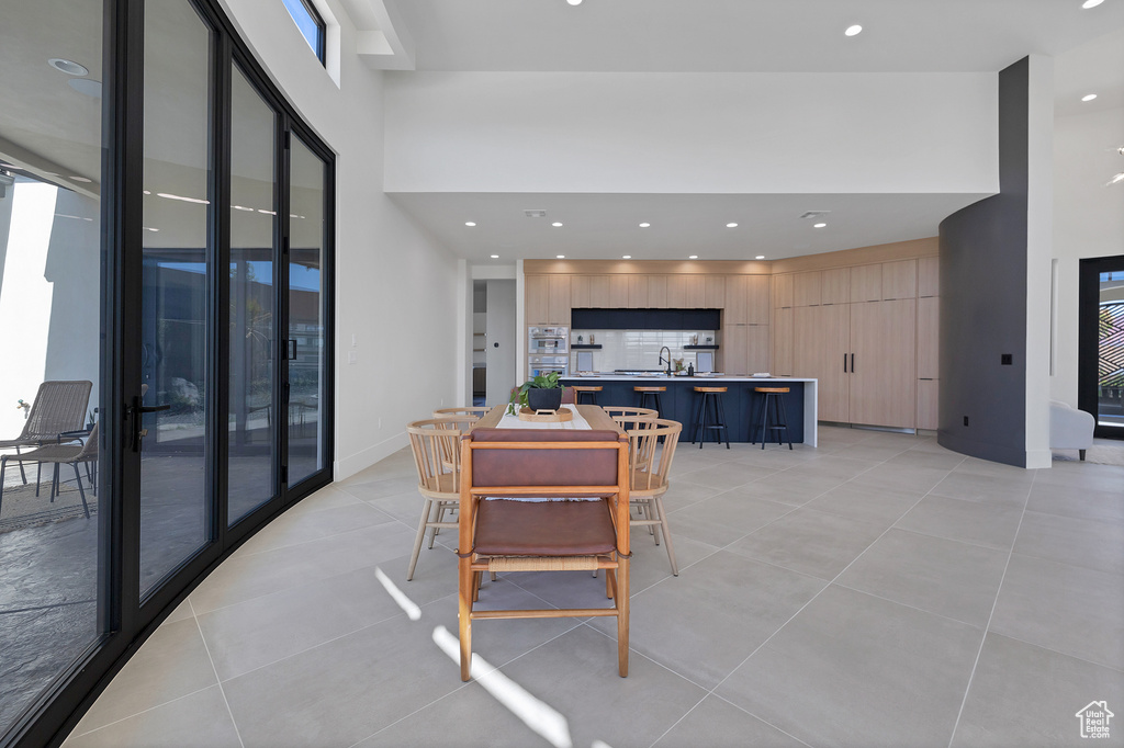 Dining space featuring a towering ceiling, plenty of natural light, sink, and light tile patterned flooring