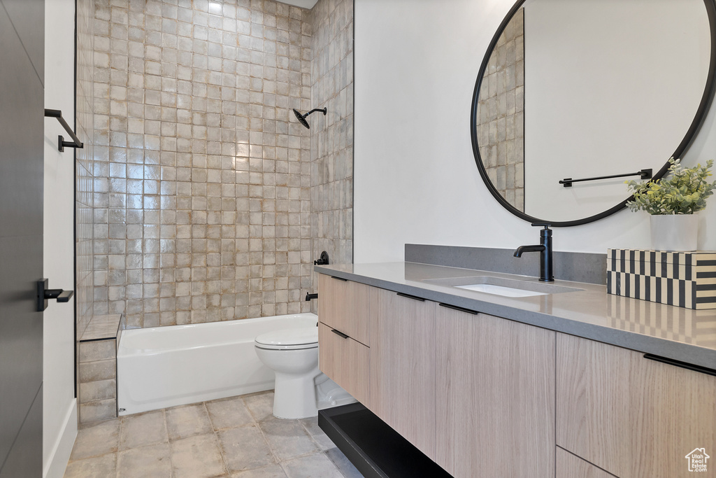 Full bathroom featuring vanity, tiled shower / bath combo, and toilet