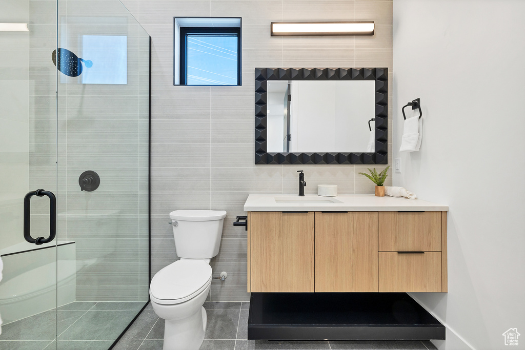 Bathroom featuring vanity, walk in shower, tile patterned floors, and tile walls