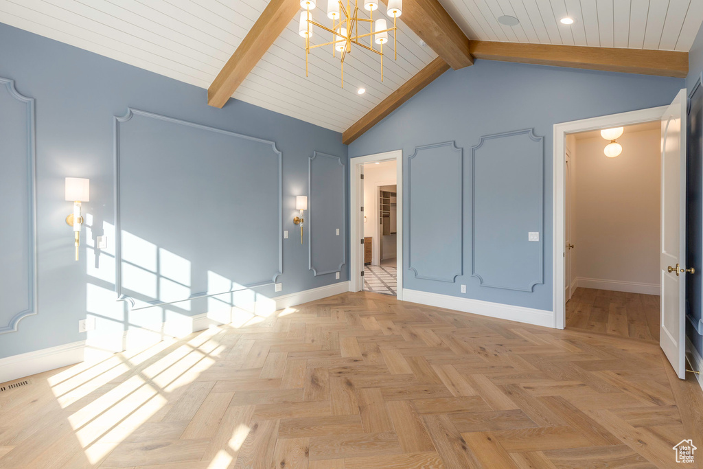 Empty room featuring an inviting chandelier, beamed ceiling, light parquet floors, and high vaulted ceiling