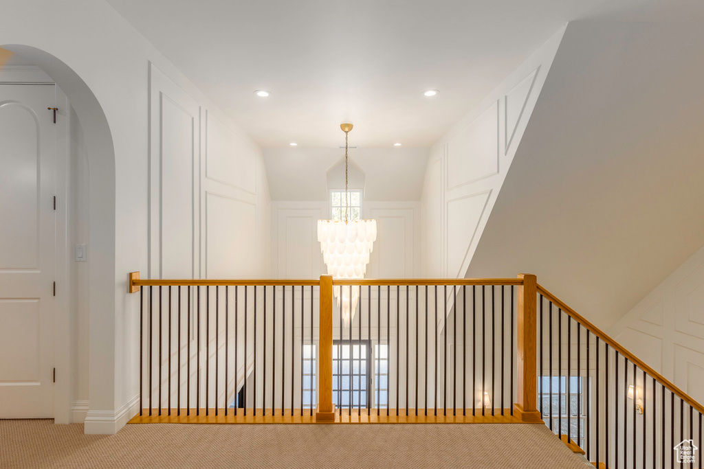 Hall featuring an inviting chandelier, vaulted ceiling, and carpet