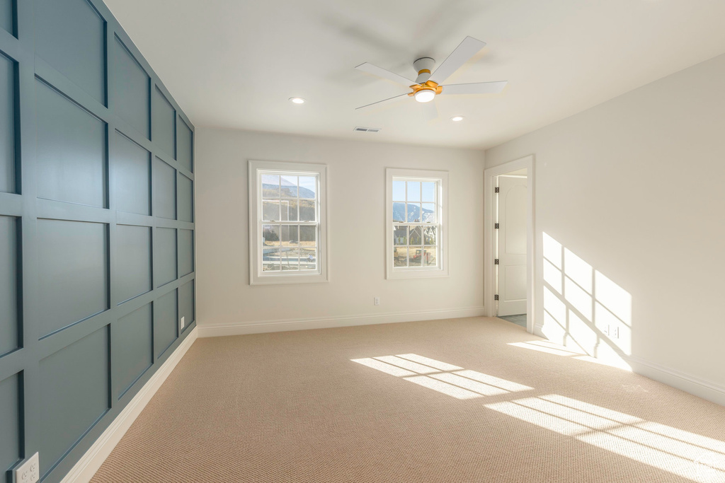 Carpeted spare room featuring ceiling fan