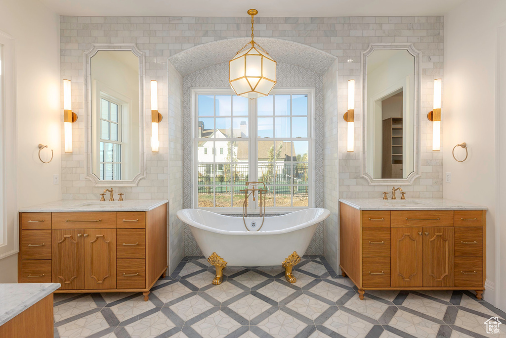 Bathroom featuring vanity, a washtub, and tile walls