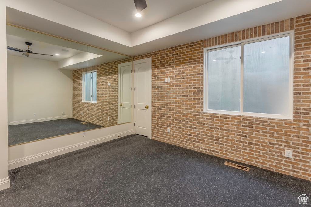 Spare room with a tray ceiling, dark carpet, and brick wall