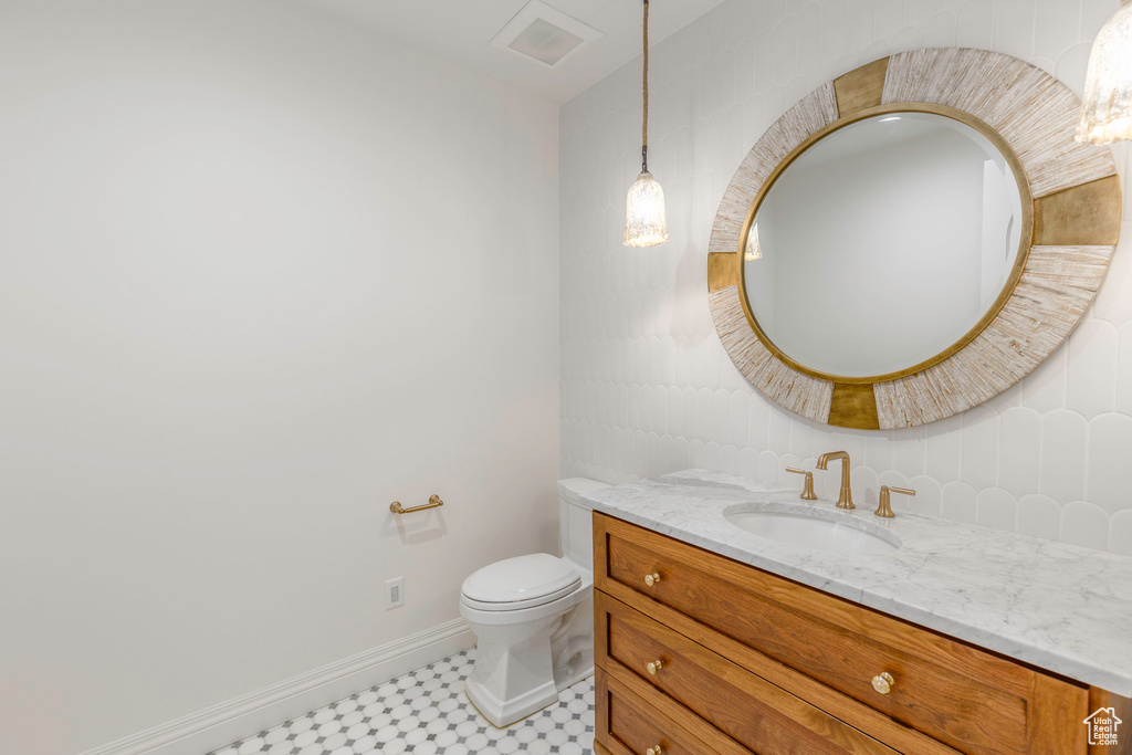 Bathroom featuring toilet, backsplash, vanity, and tile walls