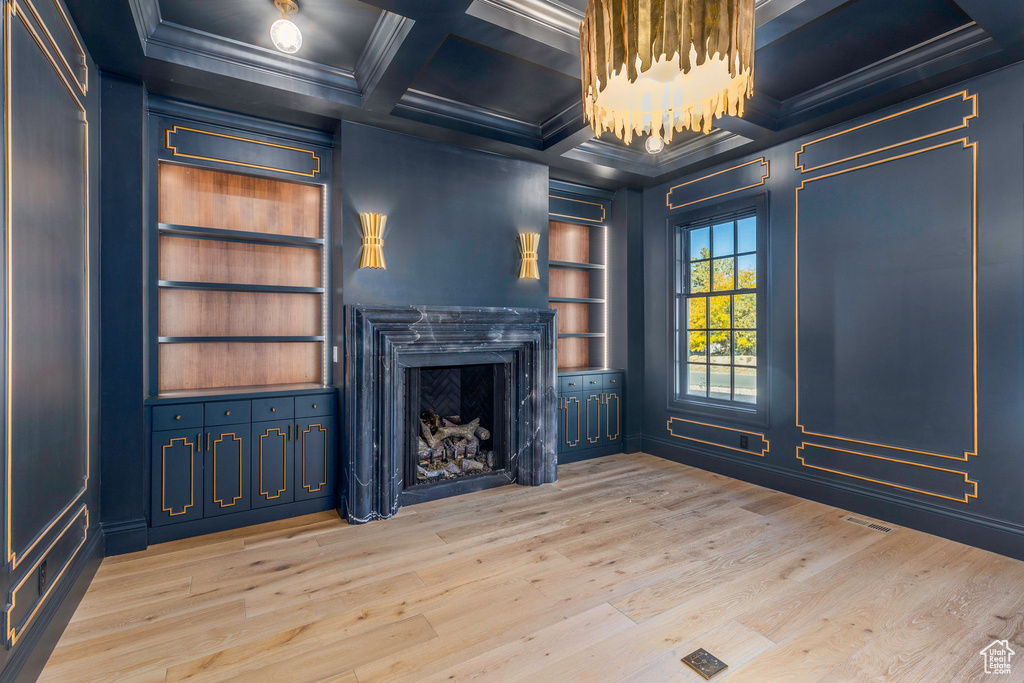 Unfurnished living room with built in features, wood-type flooring, crown molding, beam ceiling, and coffered ceiling